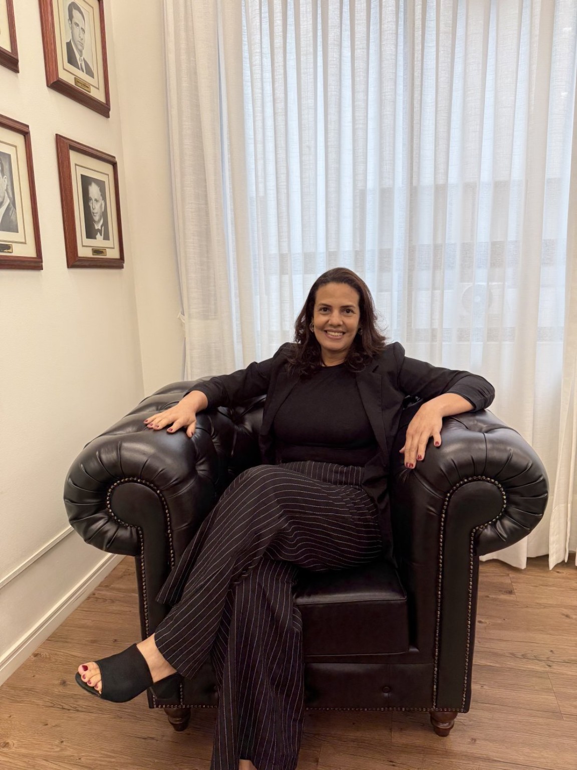 Gilmara Sena sorrindo, sentada em uma poltrona